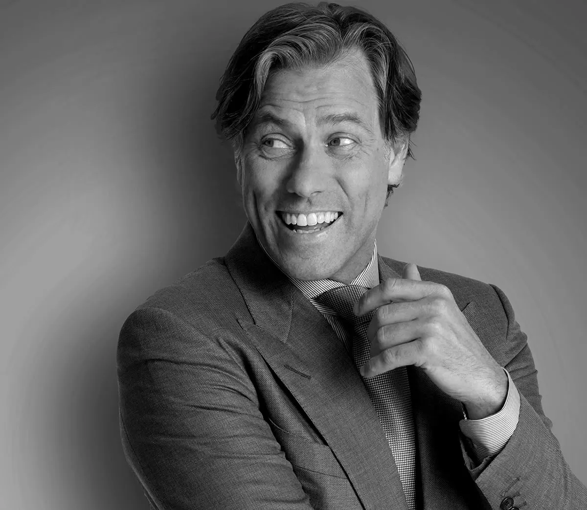 Smiling performer in a suit adjusting his tie.